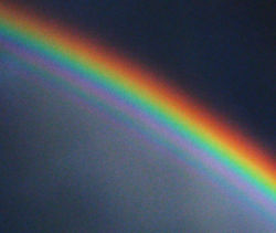 A contrast-enhanced photograph of a supernumerary rainbow, with additional green and purple arcs inside the primary bow.