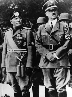 Benito Mussolini and Adolf Hitler stand together on an reviewing stand during an official visit to occupied Yugoslavia