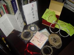 A selection of different qin strings. Top to bottom: 〖太古琴絃〗 Taigu Silk Qin Strings [中清 zhongqing gauge] with a container of 'string gum' 「絃膠」, 〖上音牌琴弦〗 Shangyin Shanghai Conservatorie Quality Qin Strings (metal-nylon), 〖虎丘古琴絃〗 Huqiu Silk Strings