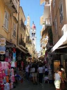 The bell tower of the church of St. Spyridon can be seen in the background among the busy kantounia of the city of Corfu.