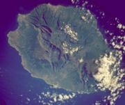 Réunion from space (NASA image). The three cirques, forming a kind of 3-leafed clover shape, are visible in the central north of the image. Piton de la Fournaise, in the south east, is covered by cloud.