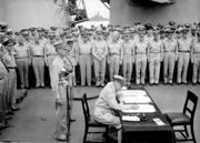 The signing of the Japanese surrender; MacArthur (sitting), behind him are Generals Percival and Wainwright.