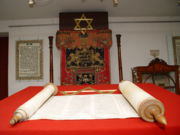 The Torah, or Jewish scripture. In the background are the Star of David and a Menorah, two important symbols of Judaism.