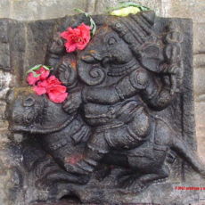 Ganesha riding on his mouse. Note the flowers offered by the devotees. A sculpture at the Vaidyeshwara temple at Talakkadu, Karnataka, India