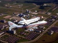 The space shuttle, atop its Boeing 747 SCA, flying over Johnson Space Center