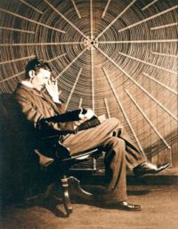 Nikola Tesla, with Rudjer Boscovich's book Theoria Philosophiae Naturalis, sits in front of the spiral coil of his high-frequency transformer at East Houston Street, New York.