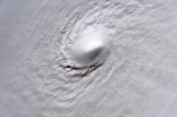 A picture of Hurricane Wilma's eye taken at 8:22 a.m. CDT October 19, 2005, by the crew aboard NASA's international space station, 222 miles above earth. At the time, Wilma was the strongest Atlantic hurricane in history, with winds near 185�mph (280�km/h) and a minimum central pressure of only 882�mbar.  Not only is this a classic example of a pinhole eye (the smallest ever observed—only 2�miles (3�km) across), but also of the stadium effect, where the eyewall slopes out and up.