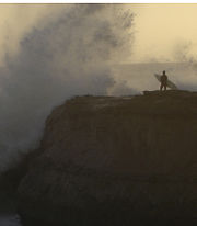 A surfer waits as a wave crashes