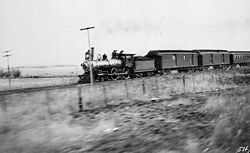 An Atchison, Topeka and Santa Fe Railway type 4-4-0 steam locomotive leads one of that railroad's passenger trains across Kansas circa 1895.