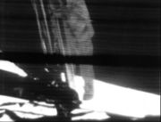 A mounted slowscan TV camera shows Neil Armstrong as he climbs down the ladder to surface