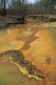 Iron hydroxide precipitate stains a stream receiving acid drainage from surface coal mining.