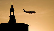 Sunset silhouettes a FedEx plane and the Bank of America Building's tower in downtown San Jose, CA, as the plane approaches Mineta San Jose International Airport.