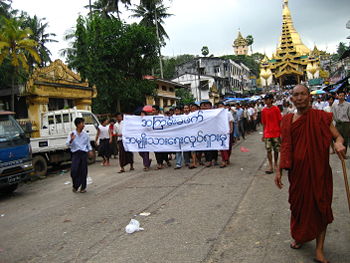 Protesters in Yangon with a banner that reads non-violence: national movement in Burmese, in the background is Shwedagon Pagoda