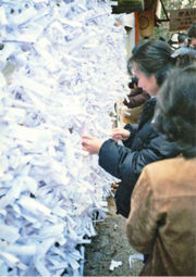 A woman tying her fortune (omikuji) at Kasuga Shrine