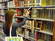 Books on library shelves with bookends, and call numbers visible on the spines