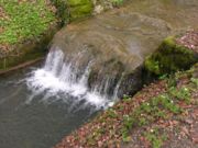 Sediment builds up on human-made breakwaters because they reduce the speed of water flow, so the stream cannot carry as much sediment load.