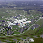 The space shuttle, atop its Boeing 747 SCA, flying over Johnson Space Center