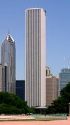 Ground-level view of an 80-story box-like skyscraper with a square cross section and a light gray exterior; thin black lines are visible running down the entire length of the building's anterior side.