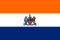 A flag with three equal horizontal stripes colored orange, white, and blue from top to bottom. In the center is the city seal (except for text and circular outline).