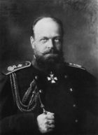 A stocky, balding man with a beard, wearing a dark military uniform.