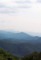 Green tree covered mountains turn blue as the progress toward the horizon.