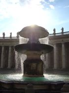 View of one fountain which rises in two tiers from a sculptured pool. The fountain is playing and the water is sparkling.