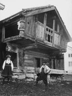 Crude log and timber open-air cabin with a pitched roof on a foundation of rocks, with the second storey overhanging the first.