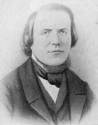 Head and bust of a man with a high forehead, hair reaching his shoulders, wearing a 19th-century three-piece suit and a cravat.