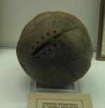 A worn, old brown football. One panel has space for stitches, but none are present.