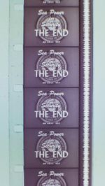 Vertical section of filmstrip, showing four-and-a-half frames, each of which reads, "Sea Power for Security. The End." Alongside the frames runs a continuous vertical white band of continuously fluctuating width.