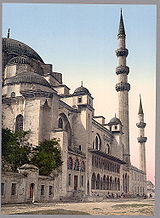 A street view of a typical Ottoman mosque, complete with a plethora of arches along the façade, several domes of various sizes, and two minarets