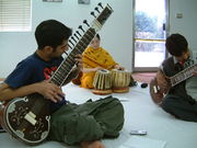 a man playing sitar dresses in white