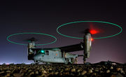  Ground crew refuel an MV-22 before a mission in central Iraq at night. The rotors are turning and the tips are green, forming green circles.