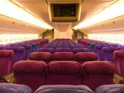 The interior of Biman's Boeing 777 aircraft showing the fronts of seats which are in various shades of indigo and violet.