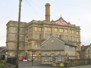 Four storey building with chimney behind gates and walls.