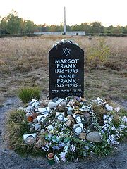 A Memorial for Margot and Anne Frank shows a Star of David and the full names and birthdates and year of death of each of the sisters, in white lettering on a large black stone.  The stone sits alone in a grassy field, and the ground beneath the stone is covered with floral tributes and photographs of Anne Frank