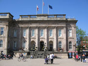 The front of a building built from grey stone with columns in front