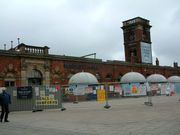 A brick building fenced off from public access with a tower and scorch marks