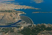 A curved dam and a large lake behind it in a hilly landscape