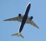 Aircraft in flight, underside view. The jet's two wings have one engine each. The rounded nose leads to a straight body section, which tapers at the tail section with its two rear fins.