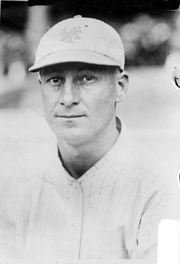 A man in a white pinstriped baseball uniform with a white baseball cap.