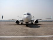 A white aircraft with green winglets parked on the ramp showing a front view