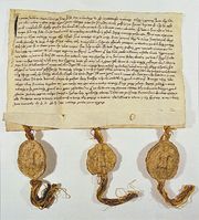 Picture of a deed which has hand-written writing on a yellowed piece of paper with three gold tassles at the bottom