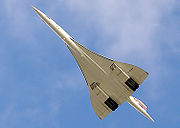 A view from below of an aeroplane in flight, with a slender fuselage and swept back wings.