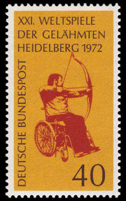 A postage stamp with a man sitting in a wheelchair shooting a bow and arrow framed by an orange background.  The wording on the stamp says, "XXI. Weltspiele Der Gelähmten Heidelberg 1972 Deutsche Bundespost"