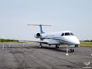 A twin-engine jet is parked on an airport ramp. The right wing has a normal upturned winglet, while the right wing has its winglet broken off.