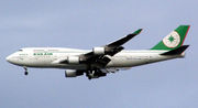 Aircraft in flight. Side view of quad-engine jet with extended landing gear and flaps.