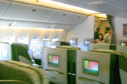 Airline business class cabin. Seats arranged in twos, with forward display screens.