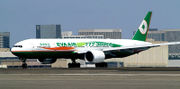 Side view of twin-jet aircraft on runway in front of airport buildings.