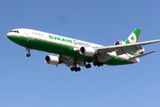 Side view of tri-jet aircraft in flight, with deployed landing gear.